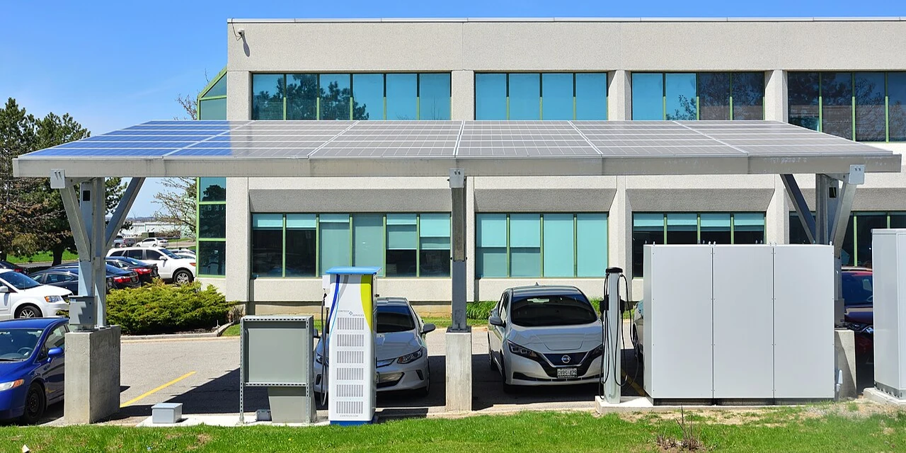 Vehículos eléctricos cargando junto a una marquesina con paneles solares